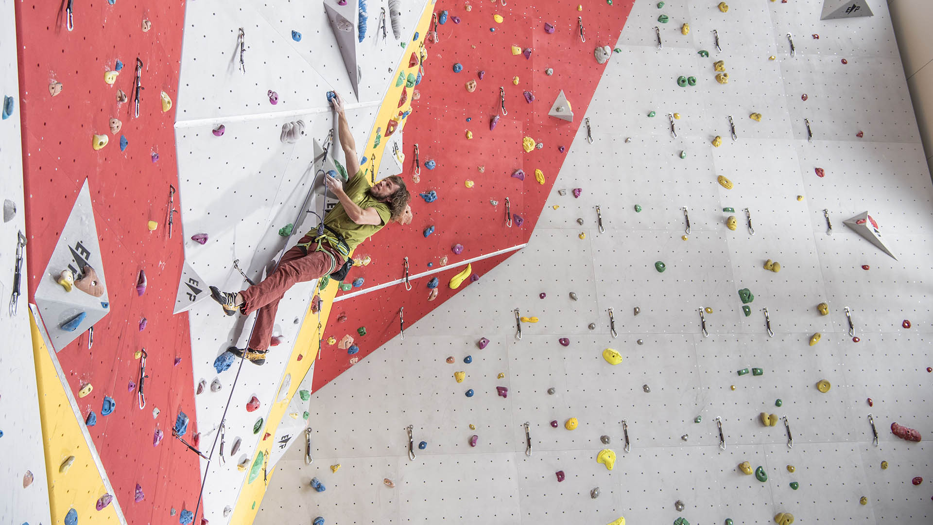 A man is roped up in an indoor climbing hall.